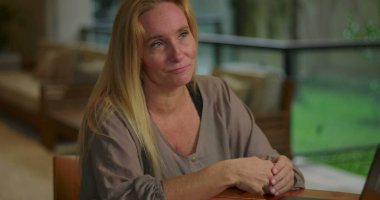 Ofis toplantısı sırasında ahşap masadaki açık dizüstü bilgisayarın önünde el kol hareketi yapan bir kadın.