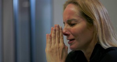 Ağlayan iş kadını, ofiste duygusal kriz anlarında elleri ve gözleri kapalı dua eder, güç ve ilahi müdahale ister.