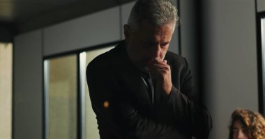 Düşünceli bir işadamı, şirket tartışması sırasında ciddi bir karar verirken el pençe divan duruyor.