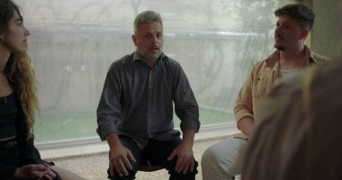 Terapi grubunun önünde erkek katılımcı açılır, derin duygular ifade ederken diğerleri yoğun paylaşım anında destek çemberi içinde dinlerler. 