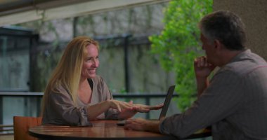 Açık ofis ortamında dizüstü bilgisayarla yapılan takım toplantısında erkek arkadaşa kadın profesyonel açıklama fikri 