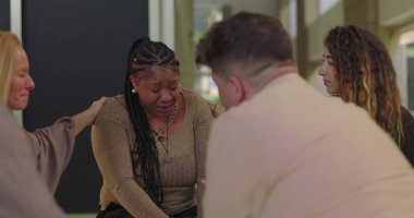 Destek grubu üyeleri ağlayan kadını teselli etmeye çalışıyor. Duygusal çöküntü, empati ve iyileşme camiası ortamında teşvik ile karşılandı. 