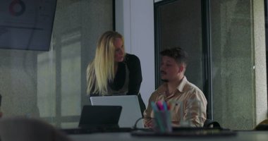 Modern ofis konferans odasındaki çalışma oturumunda erkek meslektaşına yardımcı olan kadın yönetici. 