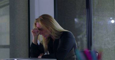 Profesyonel bir kadın duygusal yorgunluk ve zihinsel aşırı yüklenme anında elleri kolları bağlı bir şekilde büroda tek başına oturuyor.