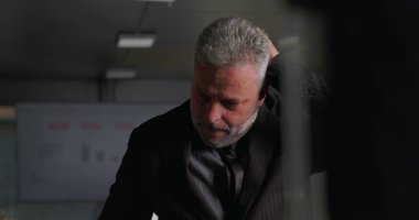 Stresli iş adamı, yüksek baskılı şirket toplantısı sırasında ofis konferans odasında tek başına dikilirken el ele vererek yüzünü kapatıyor.