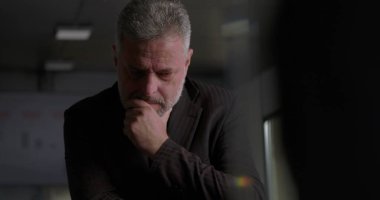 Olgun iş adamı, modern kurumsal ofis ortamında yoğun yönetim kurulu tartışması sırasında elini uzatarak düşünceye daldı.