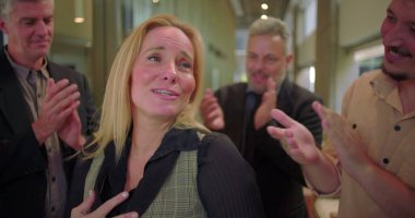 Ofis koridorundaki çeşitli iş arkadaşlarından alkış alan gülümseyen kadın, başarıyı kutlayan ve iş yerinde takdir gösteren bir grup profesyonel. 