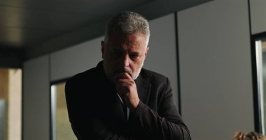 Düşünceli bir işadamı, şirket tartışması sırasında ciddi kararları değerlendirirken el pençe divan duruyor. 