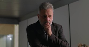 Stresli iş adamı, yüksek baskılı şirket toplantısı sırasında ofis konferans odasında tek başına dikilirken el ele vererek yüzünü kapatıyor.