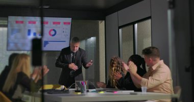 Modern ofis yönetim kurulu toplantısında başarılı bir sunumdan sonra takım liderini alkışlıyor.