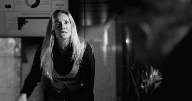 Kadın patron arka planda bağırırken, erkek çalışan yoğun baskı altındayken, yüksek bahisli ofislerde duygusal gerginlik ve hesap verilebilirliği simgeliyor.