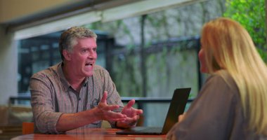 Erkek, ofis toplantısı sırasında dizüstü bilgisayarla kadınlara iş fikirleri sunarken kendini ifade ediyor.