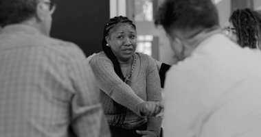 Yoğun terapi seansında ağlayan kadını teselli eden destek grubu el ele tutuşup iyileşme çemberinde duygusal güvence sunuyor.