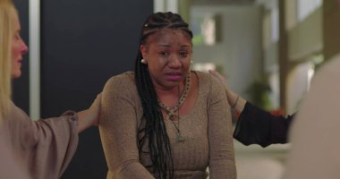 Destek grubu üyeleri ağlayan kadını teselli etmeye çalışıyor. Duygusal çöküntü, empati ve iyileşme camiası ortamında teşvik ile karşılandı.