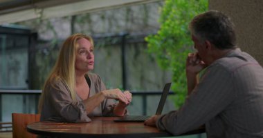 Açık ofis ortamında masadaki dizüstü bilgisayarla erkek arkadaşa kadın profesyonel açıklama fikri