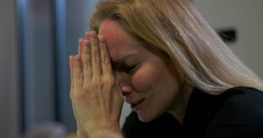 Ağlayan iş kadını, ofiste duygusal kriz anlarında elleri ve gözleri kapalı dua eder, güç ve ilahi müdahale ister. 