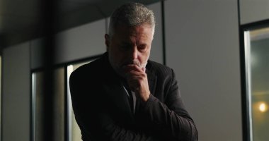 Düşünceli bir işadamı, şirket tartışması sırasında ciddi bir karar verirken el pençe divan duruyor.