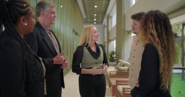 Ofis koridorunda kadın profesyonel konuşma, çeşitli iş arkadaşları modern şirket ortamında gündelik iş yeri tartışması sırasında dinleme