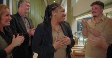 Çeşitli takımlar şirket koridorunda alkışlarken mutlu kadın gülümsüyor. Profesyoneller iş ortamında cesaret ve birlik gösteriyor.