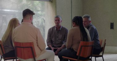 Grup terapisi sırasında başları eğik bir şekilde sessizce oturan adam diğerlerinin sessizce izlediği gibi, sakin ve düşünceli bir şekilde çemberin içinde toplandı.