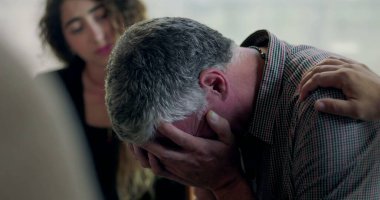 Bir erkek terapi seansı sırasında duygu yoluyla konuşmaya çalışırken diğer bir üye de kırılganlık ve bağlantı anında omuz omuza destek veriyor.