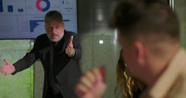 Öfkeli yönetici, gergin ofis toplantısında çalışanlarla yüzleşirken, takım üyeleri konferans masasının etrafında kaygı ve utançla tepki veriyorlar.