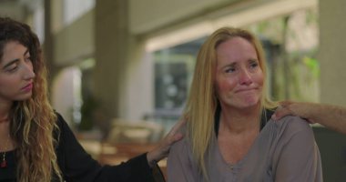 Duygusal paylaşımdan sonra grup üyeleri tarafından teselli edilen bir kadın, grup terapisi seansı sırasında gözyaşı dolu bir rahatlık ve iletişim anı.