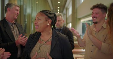 Çeşitli takımlar şirket koridorunda alkışlarken mutlu kadın gülümsüyor. Profesyoneller iş ortamında cesaret ve birlik gösteriyor. 