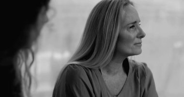 Grup terapisi sırasında ağlayan bir kadın, incinebilirlik ve yansıma anında derin acıları ifade ederken, siyah ve beyaz.