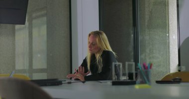 Düşünceli iş kadını boş bir ofiste tek başına oturmuş endişeli bir ifadeyle mesafeye bakıyor. Sessizce gelecek kararları ve mesleki kararsızlığı düşünüyor.