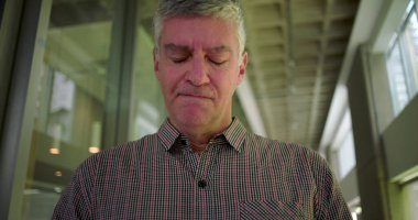Ofis koridorunda orta yaşlı bir adam gergin bir ağızla iş yerindeki stres anlarında gözle görülür endişe ve zihinsel meşguliyet gösteriyor.