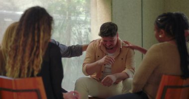 Grup terapisinde duygusal çöküntüye uğramış bir adam, destekleyici akranları arasında duygusal rahatlama ve duygusal çöküntü anlarında baş başa oturuyor.