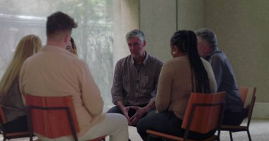 Grup terapisi sırasında başları eğik bir şekilde sessizce oturan adam diğerlerinin sessizce izlediği gibi, sakin ve düşünceli bir şekilde çemberin içinde toplandı.