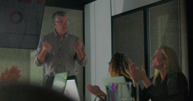 Erkek sunucu, modern konferans odasında ofis takımı toplantısında başarılı bir şekilde sunulduktan sonra motivasyon enerjisiyle gülümsüyor ve alkışları cesaretlendiriyor.