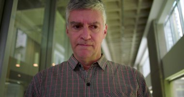 Ofis koridorunda orta yaşlı bir adam gergin bir ağızla iş yerindeki stres anlarında gözle görülür endişe ve zihinsel meşguliyet gösteriyor.