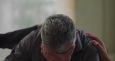 Terapi seansında, grup üyeleri sakin bir duygusal ortamda rahatlık ve destek sağlarken, erkekler el ele tutuşuyorlar.