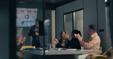 Çeşitli takımlar, modern şirket yönetim kurulundaki başarılı veri sunumunun ardından ekran görüntüleme grafiğiyle iş liderini alkışlıyor 