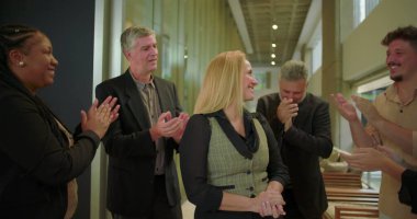 Ofis koridorundaki meslektaşlarından gülümseyen kadın profesyonel alkış alan çeşitli iş adamları, modern iş yerinde takdir ve destek gösteriyorlar.