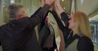 Ofis ekibi enerjik bir beşlikle kutluyor, şirket profesyonelleri birlik ve başarı içinde parlak modern koridorda duruyor.