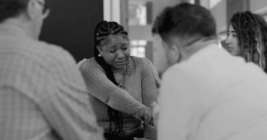 Yoğun terapi seansında ağlayan kadını teselli eden destek grubu el ele tutuşup iyileşme çemberinde duygusal güvence sunuyor.