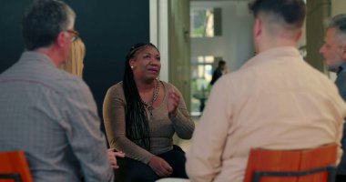 Grup terapisi sırasında kendini ifade eden bir kadın. İyileşme çemberinde oturan merhametli dinleyicilerle yeniden yapılanma ve güven anında.