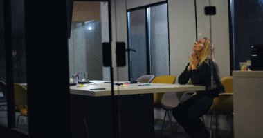 Bunalmış iş kadını konferans masasında tek başına oturuyor, yüzü ellere gömülü, yoğun işyeri stresi ve baskı altında duygusal gerginlikle başa çıkıyor.