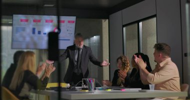 Modern ofis yönetim kurulu toplantısında başarılı bir sunumdan sonra takım liderini alkışlıyor.