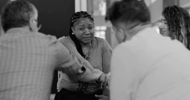 Yoğun terapi seansında ağlayan kadını teselli eden destek grubu el ele tutuşup iyileşme çemberinde duygusal güvence sunuyor.