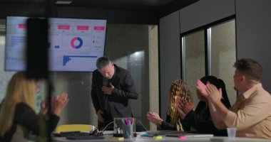 Modern ofis yönetim kurulu toplantısında başarılı bir sunumdan sonra takım liderini alkışlıyor. 