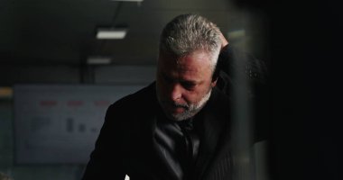 Kurumsal gerileme sırasında gergin ofis toplantısında saçlarını yolarken sinirli iş adamı duygularını zapt ediyor.