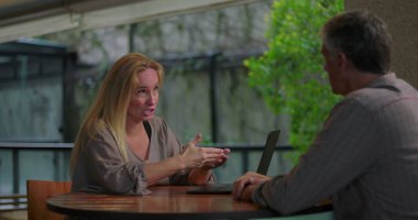 Açık ofis ortamında masadaki dizüstü bilgisayarla erkek arkadaşa kadın profesyonel açıklama fikri