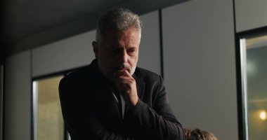 Düşünceli bir işadamı, şirket tartışması sırasında ciddi bir karar verirken el pençe divan duruyor.