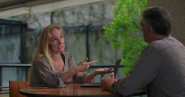 Açık ofis ortamında masadaki dizüstü bilgisayarla erkek arkadaşa kadın profesyonel açıklama fikri