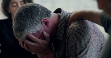 Bir erkek terapi seansı sırasında duygu yoluyla konuşmaya çalışırken diğer bir üye de kırılganlık ve bağlantı anında omuz omuza destek veriyor.